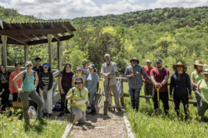 Members of the Texas Master Naturalist North Texas Chapter in a tree covered landscape with shovels and tools.